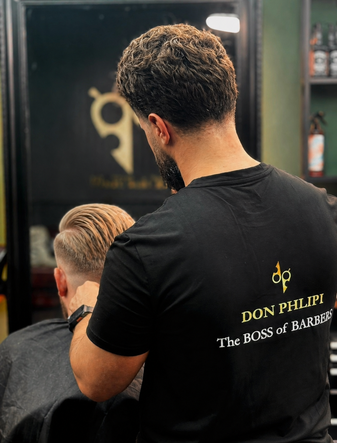 Barber at Don Phlipi Barbershop cutting a client's hair in the shop